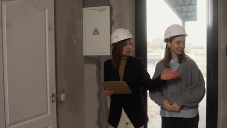 Mujeres-Con-Cascos-De-Seguridad-Caminando-En-Una-Casa-En-Construcción