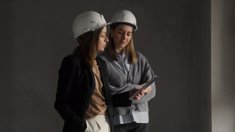 Mujeres-Con-Cascos-De-Seguridad-Hablando-En-Una-Casa-Vacía