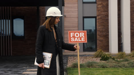 Woman-putting-for-sale-banner-on-garden