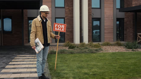 Man-putting-for-sale-banner-on-garden