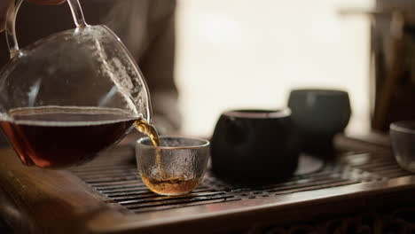 Woman-filling-glass-cup-with-black-tea