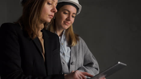 Mujeres-Con-Cascos-De-Seguridad-Hablando-En-Una-Casa-Vacía