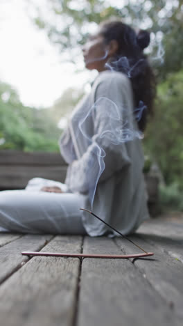 Vertical-video-of-focused-biracial-woman-practicing-yoga-in-sunny-garden,-slow-motion