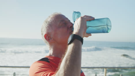 Hombre-Mayor-Bebiendo-Agua-En-El-Paseo-Marítimo