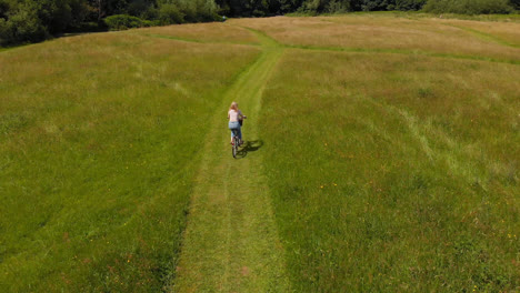 Woman-riding-bicycle-in-green-field-4k