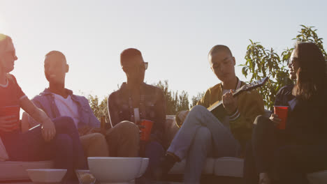 Young-man-playing-guitar-on-a-rooftop-with-his-friends