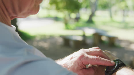 Primer-Plano-De-Un-Hombre-Mayor-Usando-Un-Teléfono-Inteligente-En-El-Parque