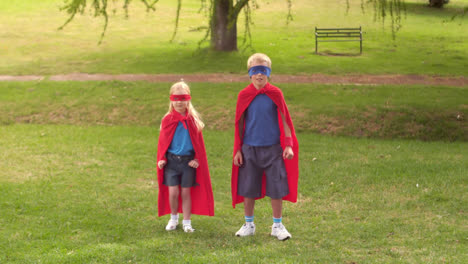 Boom-text-on-speech-bubble-against-boy-and-girl-in-superhero-costume-jumping