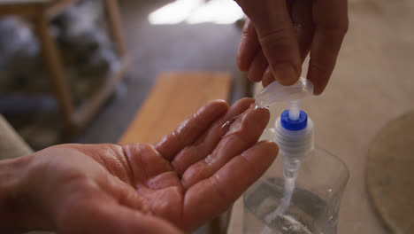 Close-up-view-of-potter-using-hand-sanitizer-at-pottery-studio