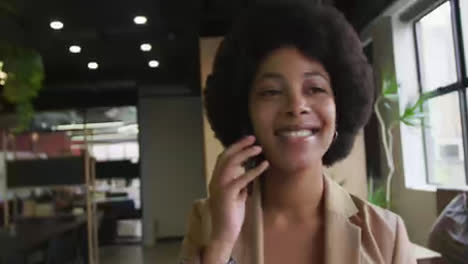 Mixed-race-businesswoman-standing-talking-on-a-smartphone-in-a-modern-office