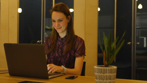 Front-view-of-young-caucasian-businesswoman-checking-her-smartwatch-while-working-on-laptop-4k