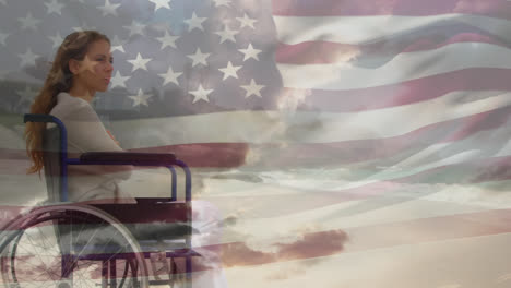 Disabled-caucasian-woman-at-the-beach-with-US-flag-waving-foreground