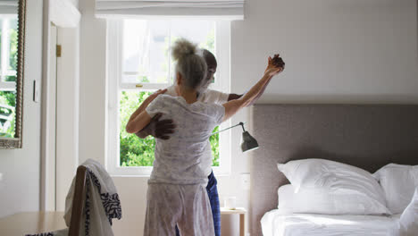 Pareja-De-Ancianos-De-Raza-Mixta-Bailando-Juntos-En-El-Dormitorio-En-Casa