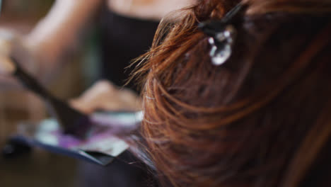 Female-hairdresser-dying-hair-of-female-customer-wearing-face-mask-at-hair-salon