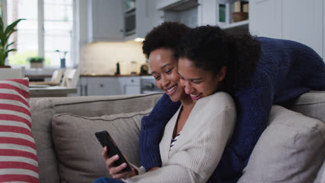 Mixed-race-lesbian-couple-sitting-on-couch-and-