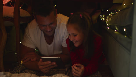 Padre-E-Hija-Caucásicos-Acostados-Y-Usando-Una-Tableta-Digital-Bajo-Una-Manta-Fuerte-Durante-La-Navidad-En-