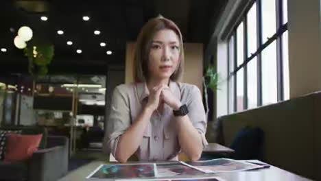 Asian-businesswoman-having-a-video-chat-going-through-paperwork-modern-office