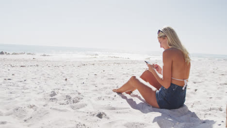 Kaukasische-Frau-Mit-Ihrem-Smartphone-Am-Strand