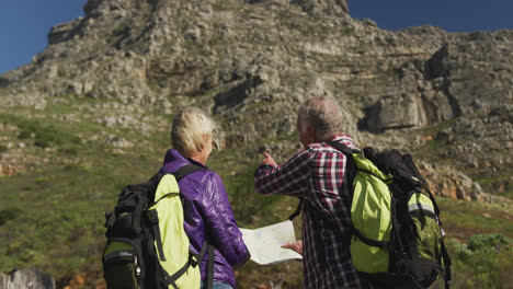 Active-senior-couple-looking-map-on-mountains