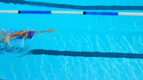 Vista-De-ángulo-Alto-De-Una-Joven-Nadadora-Nadando-Dentro-De-La-Piscina-4k