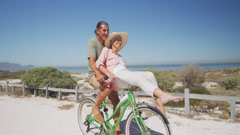 Älteres-Kaukasisches-Paar,-Das-Fahrrad-Am-Strand-Fährt