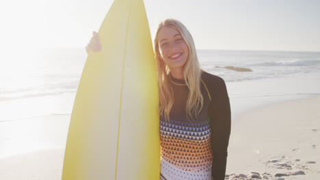 Caucasian-woman-holding-a-surfboard-on-the-beach.