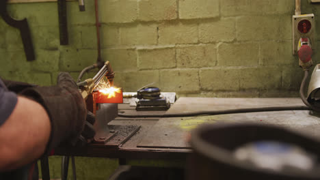 Caucasian-male-factory-worker-at-a-factory-standing-in-a-workbench-and-welding