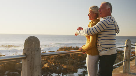 Senior-couple-embracing-each-other-alongside-beach