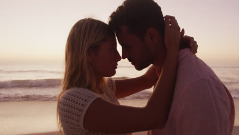 Pareja-Caucásica-Disfrutando-Del-Tiempo-En-La-Playa-Durante-La-Puesta-De-Sol