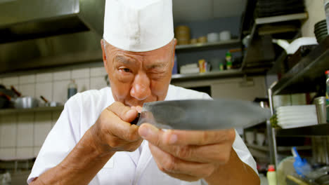 Male-chef-looking-at-knife-in-kitchen-4k