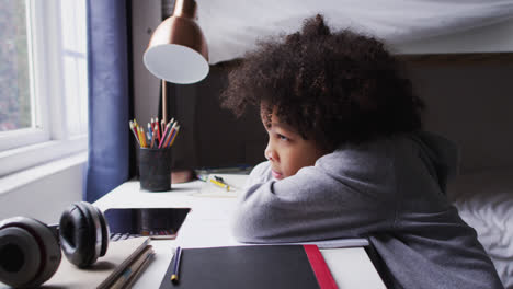 Mixed-race-girl-sitting-by-desk-looking-through-window