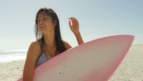 Female-surfer-with-surfboard-playing-with-her-wet-hair-4K-4k