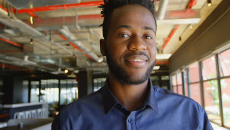 Front-view-of-happy-young-black-businessman-looking-at-camera-in-a-modern-office-4k