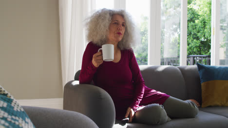 Ältere-Kaukasische-Frau-Trinkt-Kaffee-Beim-Fernsehen-Zu-Hause