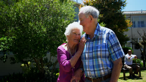 Vista-Frontal-De-Una-Pareja-De-Ancianos-Caucásicos-Activos-Caminando-En-El-Jardín-De-Una-Residencia-De-Ancianos-4k