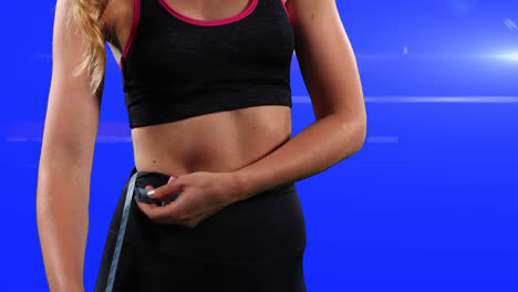 Caucasian-woman-in-sport-outfit-taking-her-measurements-in-a-blue-background-with-white-rays
