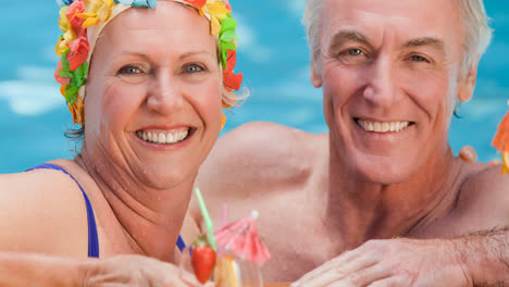 Retrato-De-Una-Pareja-Mayor-Caucásica-De-Vacaciones-Con-Un-Cóctel-En-La-Piscina