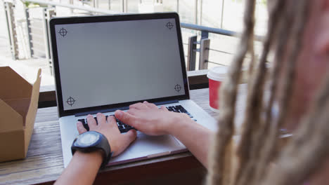 Hombre-De-Raza-Mixta-Con-Rastas-Sentado-En-Una-Cafetería-Usando-Una-Computadora-Portátil-Con-Espacio-Para-Copiar-En-La-Pantalla