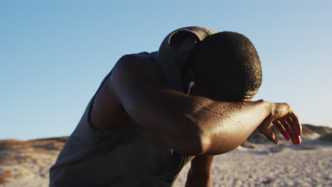 Focused-african-american-man-taking-break-in-exercise-outdoors-by-seaside