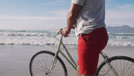 Hombre-Afroamericano-Mayor-Caminando-Con-Una-Bicicleta-En-La-Playa