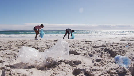 Pareja-Afroamericana-Sosteniendo-Sacos-De-Basura-Y-Recogiendo-Desechos-Plásticos-De-La-Playa