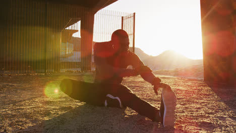 Focused-african-american-man-stretching-his-legs,-exercising-outdoors-in-the-evening