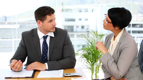 Handsome-businessman-talking-with-colleague-at-desk