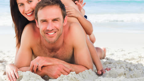 Retrato-De-Una-Familia-Caucásica-Sonriente-De-Vacaciones-Tumbada-En-La-Arena-Junto-Al-Mar