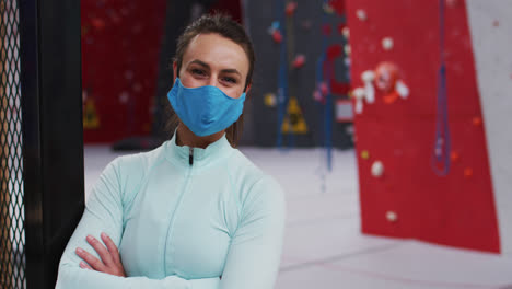 Retrato-De-Una-Mujer-Caucásica-Sonriente-Con-Mascarilla-En-Un-Gimnasio-De-Escalada-Interior