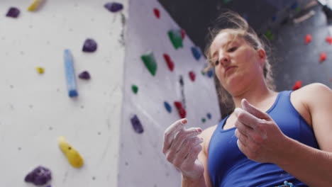 Kaukasische-Frau-Bereitet-Ihre-Hände-Mit-Kreide-Vor-Dem-Klettern-An-Einer-Indoor-Kletterwand-Vor