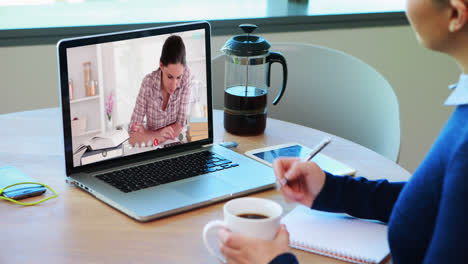 Profesora-Caucásica-Usando-Una-Computadora-Portátil-En-Una-Videollamada-Con-Una-Estudiante,-Tomando-Notas