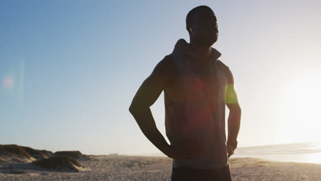 Focused-african-american-man-stretching,-exercising-outdoors-by-seaside