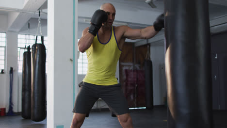 Kaukasischer-Männlicher-Trainer-Mit-Boxhandschuhen-Trainiert-Mit-Boxsack-Im-Fitnessstudio