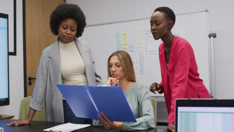 Three-diverse-businesswomen-in-discussion-looking-at-paperwork-in-an-office